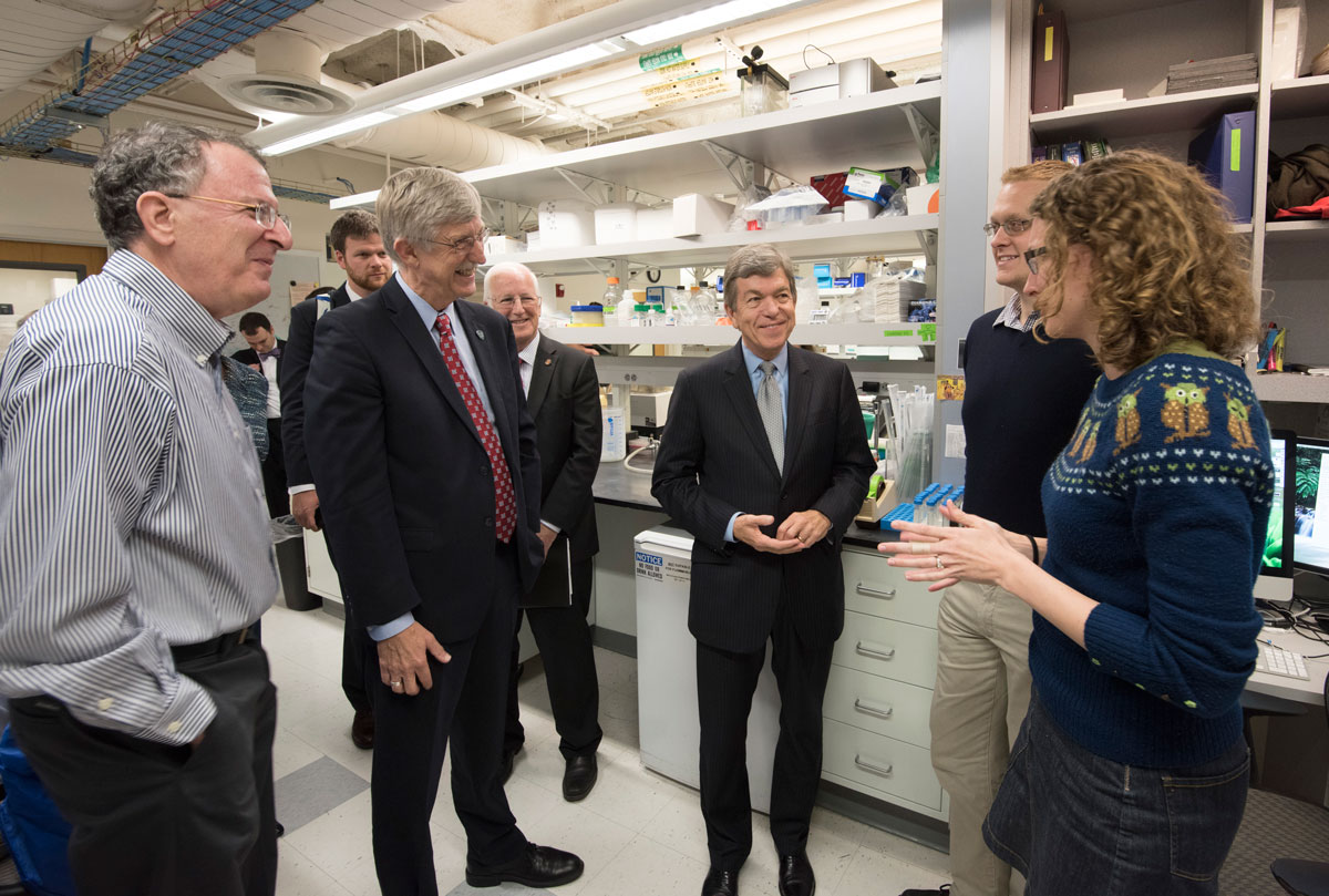 Washington University graduate student Laura VanArendonk Blanton talks about her work in Jeffrey Gordon’s lab at the School of Medicine. Listening are (from left) NIH Director Francis S. Collins; Larry J. Shapiro, MD; U.S. Sen Roy Blunt; and fellow graduate student Mark Charbonneau. The group was on a tour of medical school facilities.