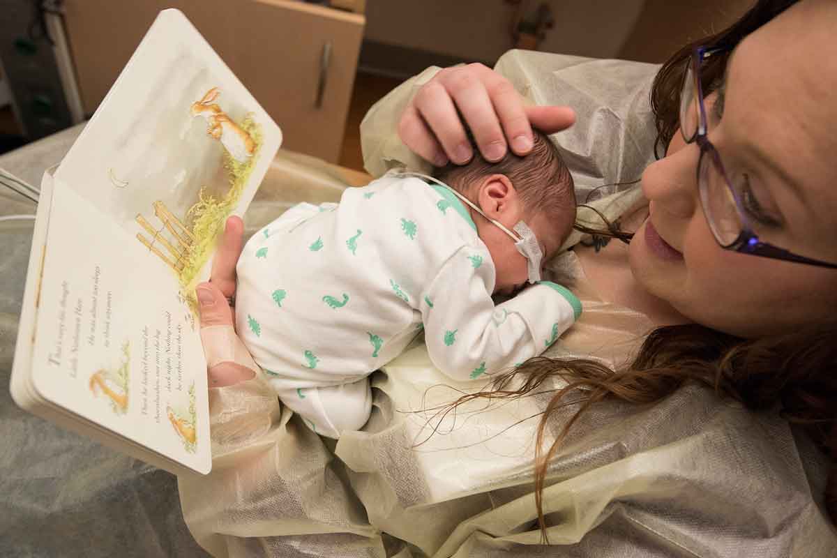 Nycole Tennant, of Trenton, Ill., reads a book to her son Kainen in the neonatal intensive care unit (NICU) at St. Louis Children's Hospital. While reading, Tennant also focuses on sensory interactions with her baby. Kainen and his twin sister, Kyzer, were born prematurely.