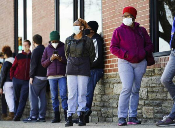 People wearing masks wait in line outside for COVID-19 vaccinations