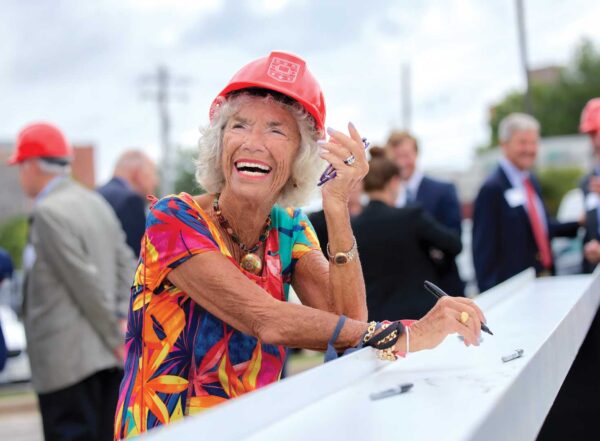 Carol B. Loeb and university leaders and guests sign the final steel beam of the Neuroscience Research Building under construction on the medical campus before the beam was placed on top of the structure.