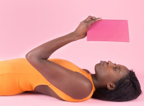 A woman lies are on her back reading a book